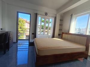 a bedroom with a bed and a desk and two windows at Tersha Homestay 2BHK in Shillong