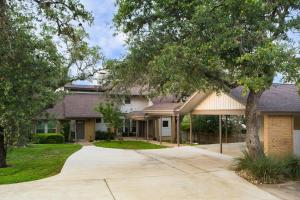 a house with a tree and a driveway at Travis by AvantStay Waterfront Lake Retreat in Lakeway