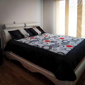 ein Bett mit einer schwarzen Decke mit roten Blumen drauf in der Unterkunft Casa Vacacional Alejandria in Paipa