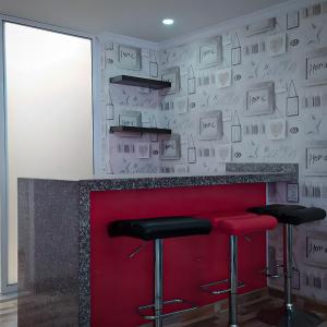 Eine Bar mit zwei Barhockern vor einem roten Tresen in der Unterkunft Casa Vacacional Alejandria in Paipa