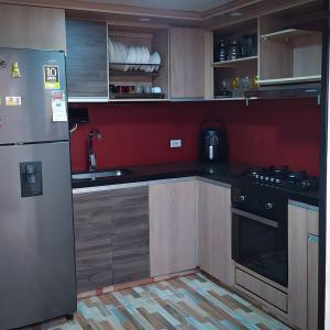 eine Küche mit Holzschränken und einer roten Wand in der Unterkunft Casa Vacacional Alejandria in Paipa