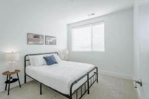 a white bedroom with a bed and a window at Cozysuites l Luxe 2BR in Downtown Cincinnati #2 in Cincinnati