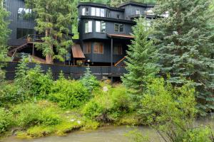 a large black house with trees and a river at Manitou River House 113 by AvantStay A Location in Telluride