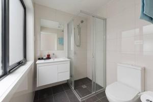 a bathroom with a shower and a toilet and a sink at Modern New 3BR Townhouse with Free Parking in Belconnen +26 photos