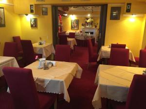 a dining room with white tables and red chairs at Hotel Galleria in Munich