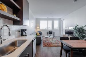 TWO Luxe CozySuites in Downtown Cincinnati في سينسيناتي: مطبخ وغرفة معيشة مع حوض وطاولة