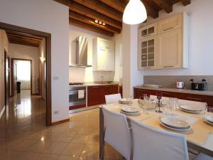 una cocina con mesa con sillas blancas y una cocina con en Cannaregio - Venice Style Apartments, en Venecia