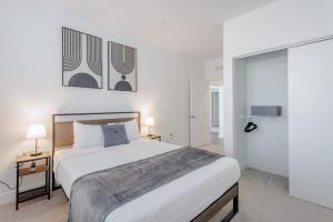 a white bedroom with a bed and two lamps at Cozysuites l Luxe 2BR in Downtown Cincinnati #5 in Cincinnati +26 photos