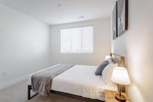 a white bedroom with a bed and a window at Cozysuites l Luxe 2BR in Downtown Cincinnati #5 in Cincinnati