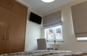 Un dormitorio con una cama y un escritorio y una ventana. en Casa d'Avenida, en Manteigas