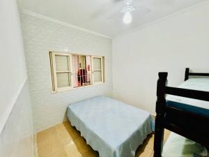 ein kleines Schlafzimmer mit einem Bett und einem Fenster in der Unterkunft Casa de 2 Quartos à 5 min a Pé da Praia, com Churrasqueira e 3 Vagas de Garagem in Praia Grande
