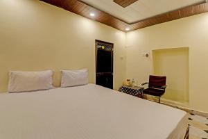 een slaapkamer met een groot wit bed en een stoel bij Hotel O Home Shyama Lodge in Ayodhya