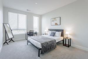 a bedroom with a bed and two tables and two windows at Cozysuites l Luxe 2BR in Downtown Cincinnati #4 in Cincinnati