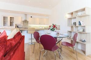 a living room with a red couch and a table and chairs at Tidemill House Apartment in Falmouth
