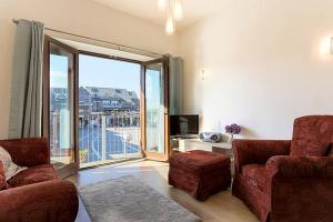 a living room with a couch and a large window at Tidemill House Apartment in Falmouth