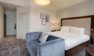 a hotel room with a large bed and a blue couch at Glasgow Grosvenor Hotel in Glasgow