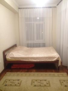 a bed sitting in a room with a window at Apartment Na Gazone in Velikiy Novgorod