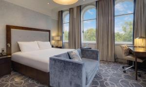 a hotel room with a bed and a desk and windows at Glasgow Grosvenor Hotel in Glasgow