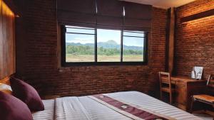 a bedroom with a bed and a brick wall at SuanGlangNa in Phrae