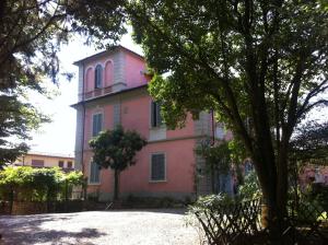 una casa rosa con un árbol delante en Villa Arianna B&B, en Lari