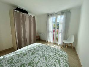 ein Schlafzimmer mit einem Bett und einem Stuhl und einem Fenster in der Unterkunft Appartement T3 rénové avec WIFI, proche des Thermes de Cambo-les-Bains - FR-1-495-145 in Cambo-les-Bains