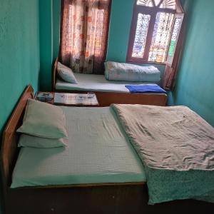 zwei Einzelbetten in einem Zimmer mit Fenster in der Unterkunft Myagdi Devisthan Guest House And Bhanchha Ghar in Pokhara