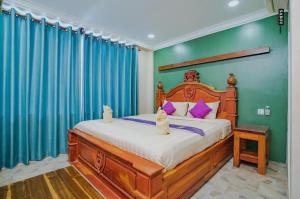 a bedroom with a large bed with blue curtains at Neakru Guesthouse and Restaurant in Kampot