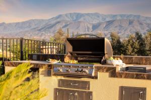 a grill on a balcony with mountains in the background at Sangiovese By AvantStay Spectacular Estate w Pool Hot Tub Putting Green in Temecula