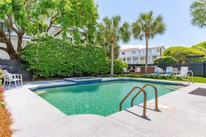 a swimming pool in a yard with chairs and trees at 3800 Cameron Boulevard AvantStay Pool Ocean Views Deck in Isle of Palms
