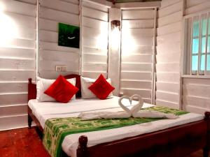 a bedroom with a bed with red and white pillows at New Kahuna Cabanas in Unawatuna