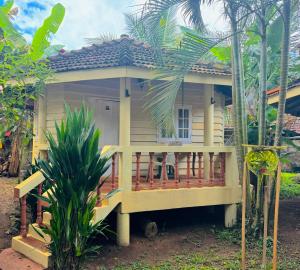 a small yellow house with a porch in front at New Kahuna Cabanas in Unawatuna
