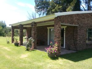 uma casa de tijolos com flores num quintal em Beaconsfield Farm em Hofmeyr