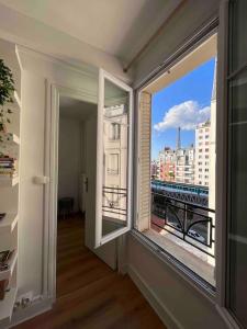 a room with a window with a view of a city at Le Point d'Eiffel - Au Cœur de Grenelle in Paris