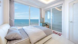a bedroom with a large window with a view of the ocean at Pohang Playbeach Poolvilla in Pohang
