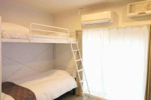 a bunk bed with a ladder next to a window at Shin Osaka Grand Heights SG51 in Osaka
