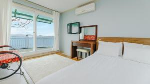 a bedroom with a bed and a desk and a window at Namhae baramundeok Pension in Namhae