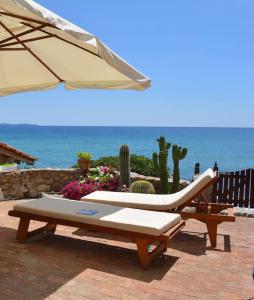 a patio with an umbrella and a couch and a table at Exclusive Tuscany beach house - The sea at your doorstep in Monte Argentario