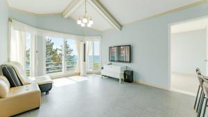 a living room with a couch and a tv and windows at Namhae baramundeok Pension in Namhae