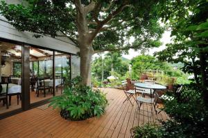 a patio with a tree and a table and chairs at 山魚亭 in Izunokuni