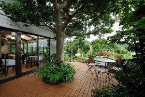 a patio with a tree and a table and chairs at 山魚亭 in Izunokuni