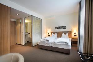 a bedroom with a large white bed and a mirror at Hotel am Jakobsmarkt in Nuremberg