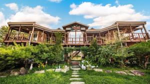 a large wooden house with a deck in the yard at Gyeongju Papaya Aegyeondongban Pension in Gyeongju