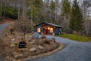 una piccola cabina con una porta rossa nel bosco di Bear’s Place by AvantStay Cozy Mountain Cabin in Brevard Firepit a Brevard