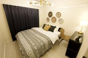 a bedroom with a bed with a black curtain and a desk at Li Kotohogi 302 in Naha