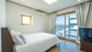 a white bedroom with a bed and a large window at Samcheok jangho sanho Pension in Samcheok