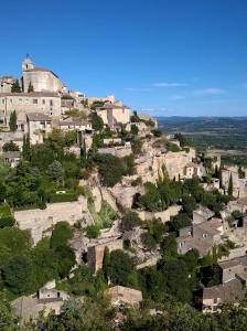 a village on a hill with houses and trees at Le Mazet Du Domaine in Gordes