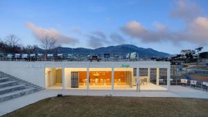 a large white building with glass doors and stairs at Ganghwado Lafamilia Pension in Incheon