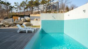a swimming pool with two lounge chairs next to it at Ganghwado Lafamilia Pension in Incheon