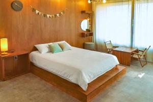 a bedroom with a large white bed and a table at Jeju sunjinhanga Pension in Seogwipo
