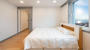 東海市にあるDonghae Hill Stay Pensionのベッドと大きな窓のある白い寝室